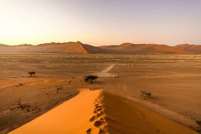 Scenic view of desert against clear sky during sunset