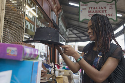 A young woman looking at a black hat.