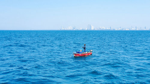 Boat sailing on sea against clear sky