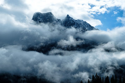 Low angle view of clouds covering mountain against sky