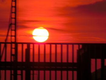 Low angle view of silhouette railing against orange sky