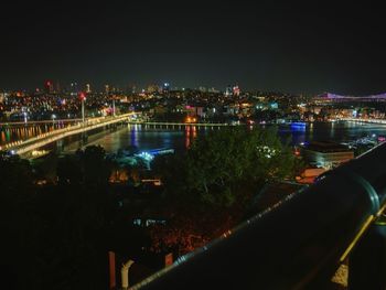 Illuminated buildings by river against sky at night