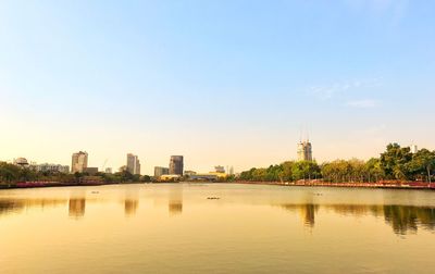 Buildings by river against sky in city