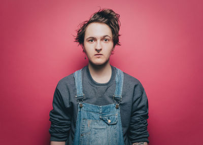 Portrait of young man standing against red background