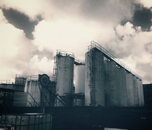 Low angle view of crane against cloudy sky