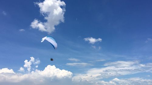 Low angle view of paragliding against blue sky