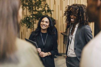Happy female entrepreneurs talking with delegates during networking event at convention center