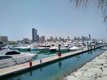 Boats moored in harbor against buildings in city