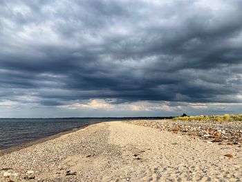 Scenic view of beach against cloudy sky