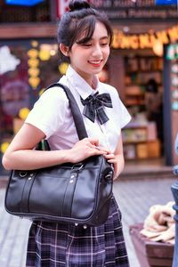 Portrait of young woman standing in city