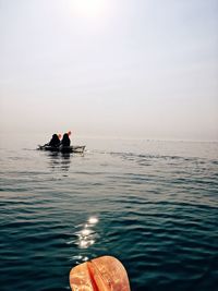 Silhouette people in boat on sea against sky