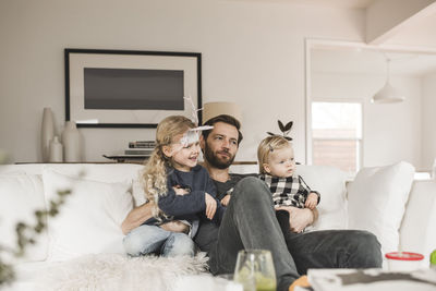 Mid adult man with daughters sitting on sofa in living room at home