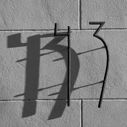 Close-up of shadow of house number 13 on brick wall