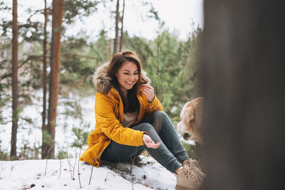 Woman sitting on snow covered tree