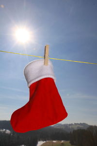 Close-up of santa stocking drying on clothesline against sky during sunny day