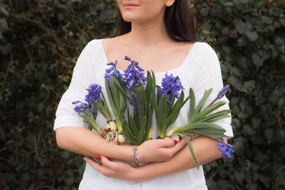 Midsection of woman holding purple flower