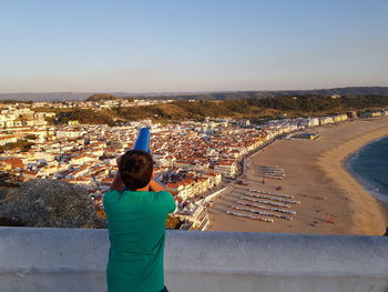 Rear view of man looking at cityscape against sky