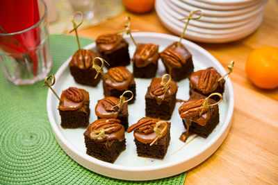 Slices of chocolate biscuit with caramel sauce and pecans on top. canape dessert.