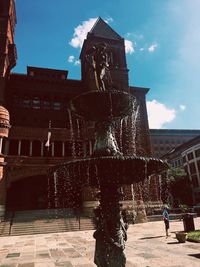 Fountain in front of building against sky