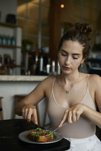 Young woman having food at table in cafe