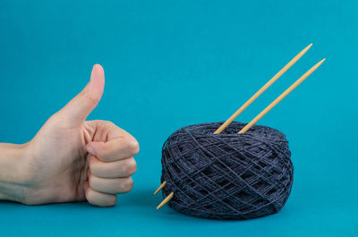 Close-up of hands on blue table against wall