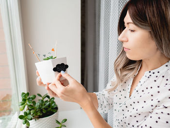 Beautiful woman decorating plant at home