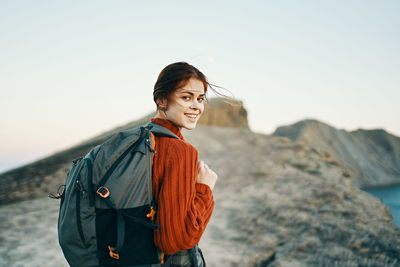 Young woman standing on rock against clear sky