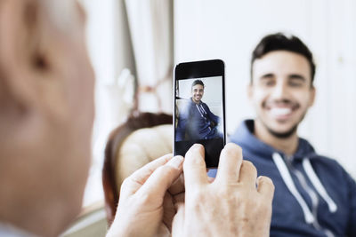 Senior man photographing caretaker through mobile phone