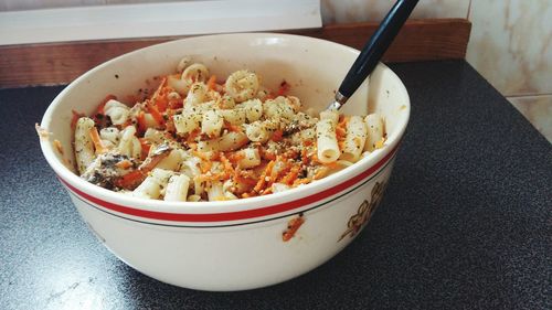 Bowl of pasta with spoon served on table