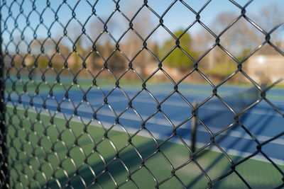 Full frame shot of empty tennis courts through chainlink fence