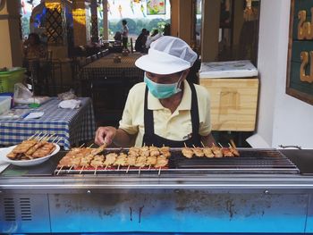 Man preparing food on barbecue grill at market