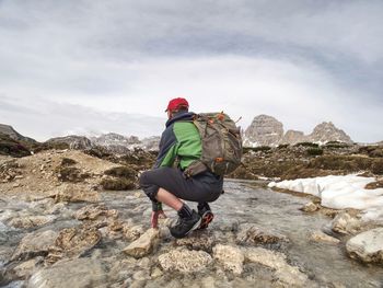 Hiker man with backpack crossing stream on stones in dolomiti mountains. hiking and leisure theme