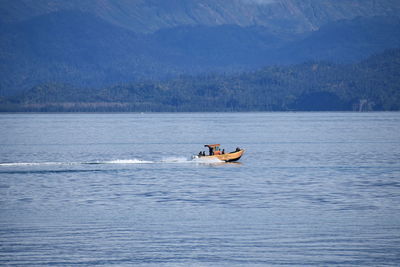 Boat sailing on sea against mountains