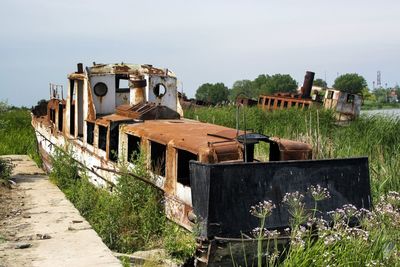Abandoned boat on field against sky
