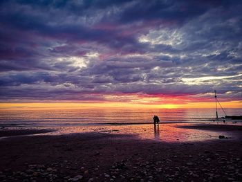 Silhouette person on beach against sky during sunset