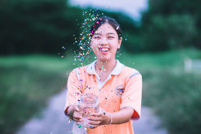 Smiling young woman throwing confetti