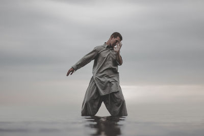 Man exercising in sea against sky