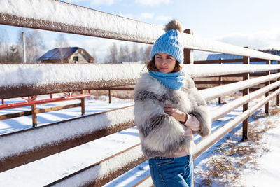 A young woman in a blue knitting hat, white fur coat enjoys winter nature, posing 