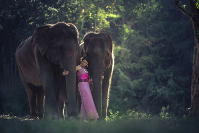 Girl standing on field against trees