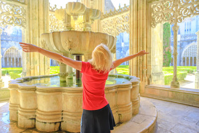 Woman with arms outstretched standing against fountain