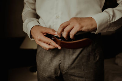 Midsection of man getting dressed while standing at home