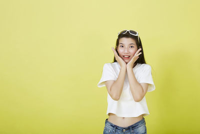 Portrait of girl standing against yellow background