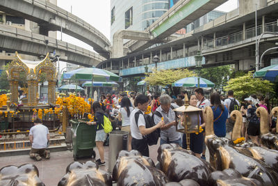 People standing by religious statue during event against buildings