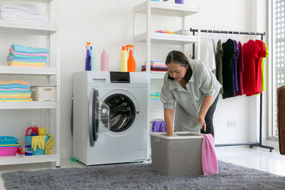 Senior woman putting clothes in washing machine