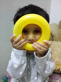 Portrait of cute girl holding yellow mask