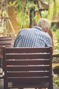 Rear view of man sitting on bench in park