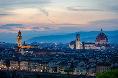 Illuminated buildings in city against sky