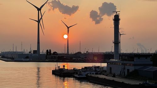 Sailboats moored on sea against sky during sunset