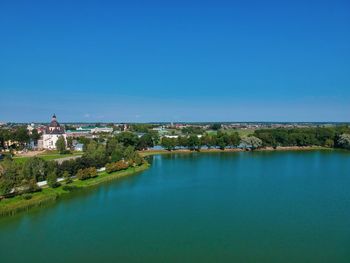 Scenic view of lake by buildings against clear blue sky