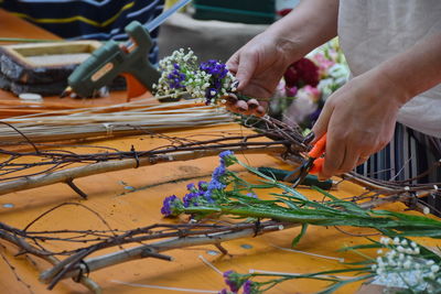 Midsection of florist cutting flowers on table in shop